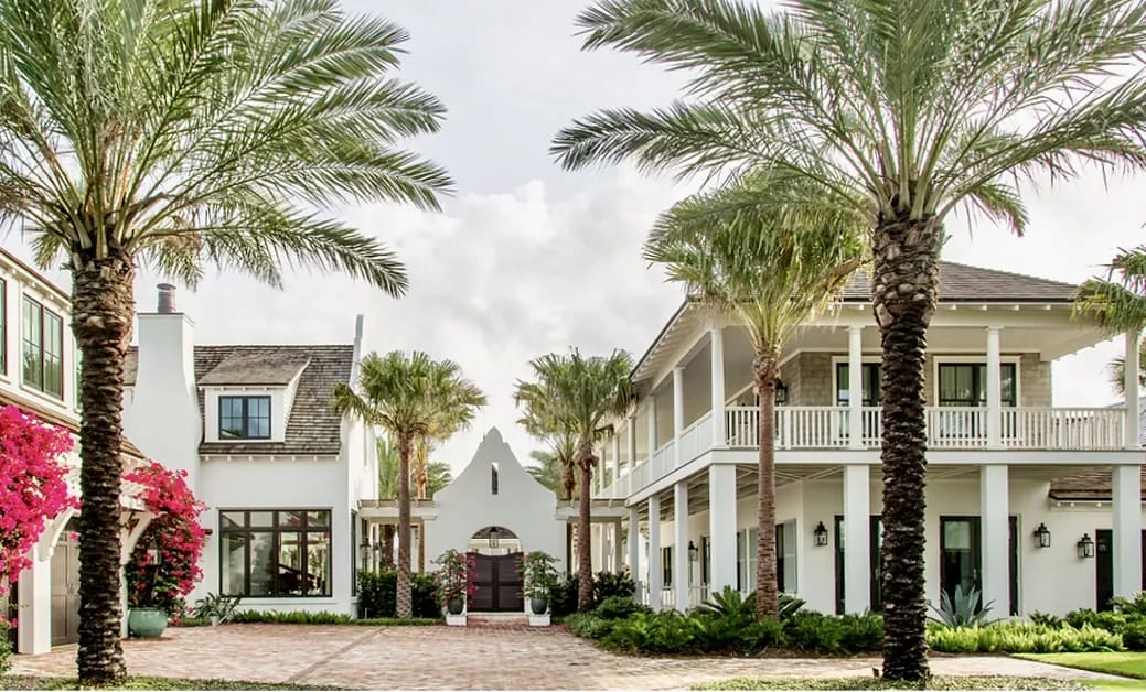 Exterior front view with two structures, balconies, palm trees, and brick paving.