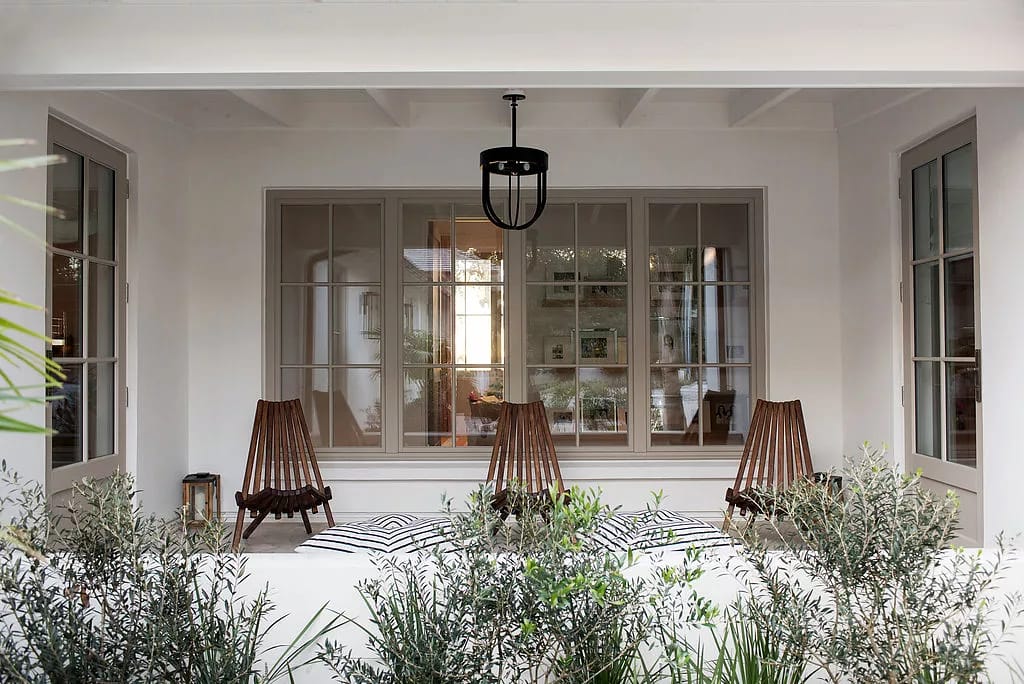 Patio with two wooden chairs, outdoor rug, greenery, and pendant light above