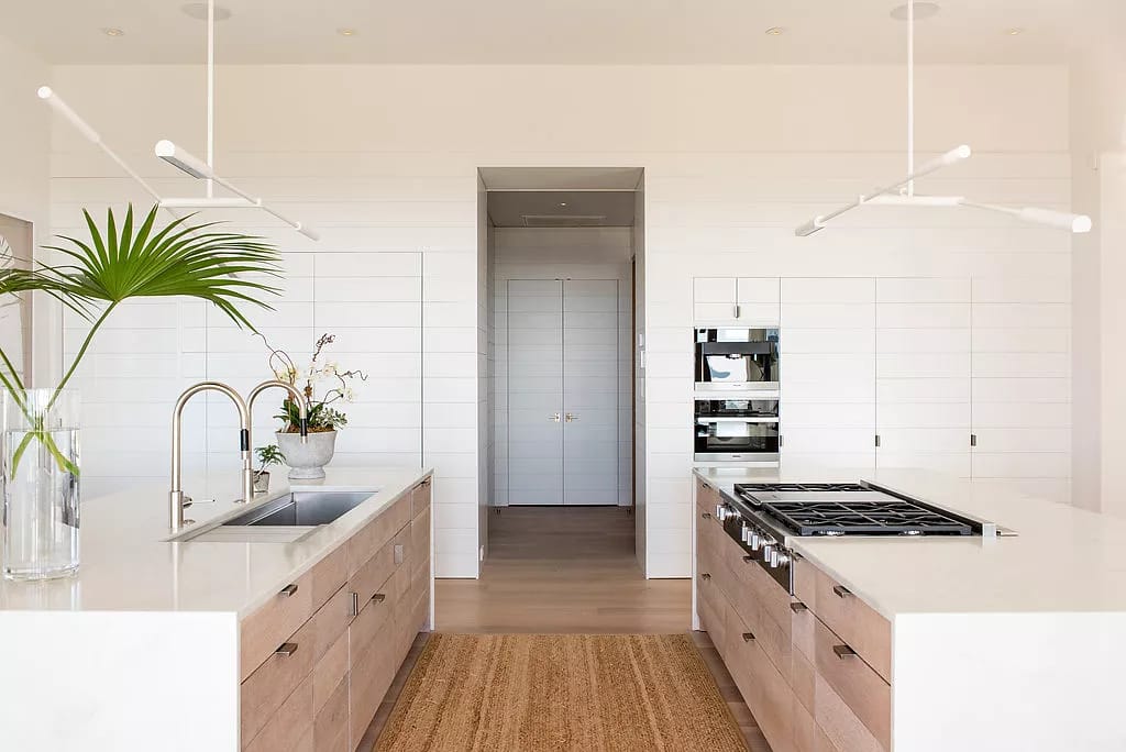 Kitchen with light wood cabinets, central island, white stone countertops, and hanging pendant lights