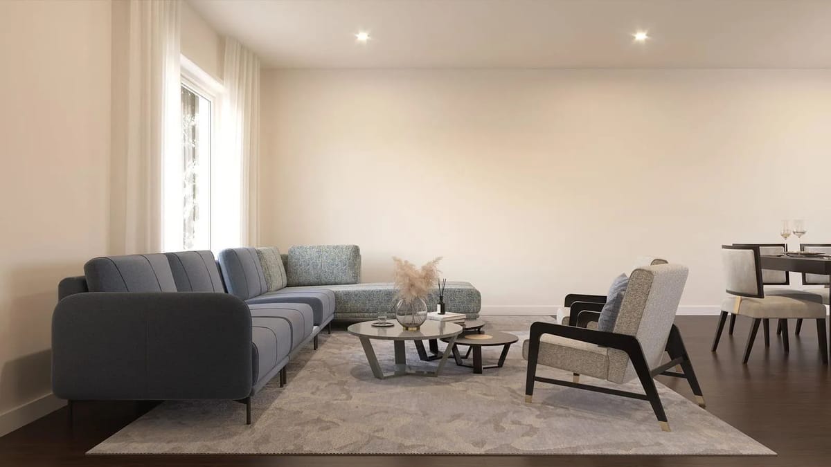 Living room with blue sectional sofa, patterned armchairs, round coffee table, and large windows with dark wood flooring.