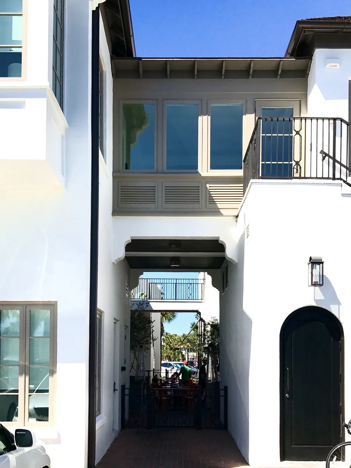 Exterior front view of a two-story house with balcony, black door, and patio area.