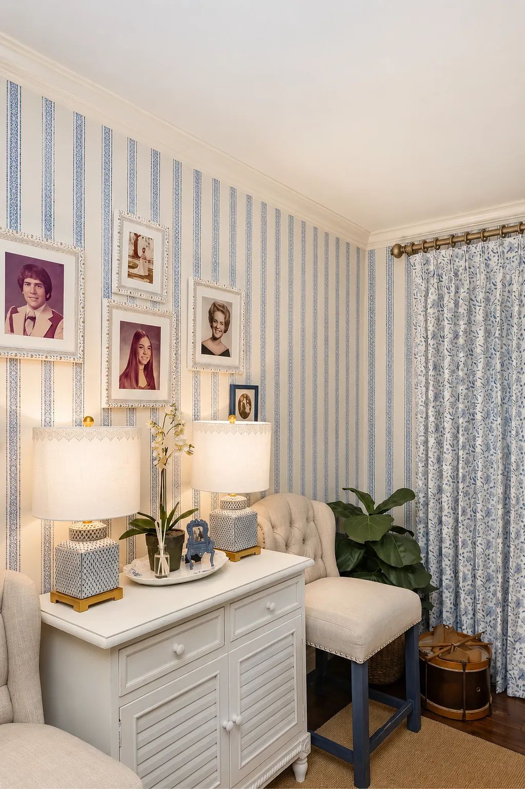 Small room with tufted armchair, console table, patterned wallpaper, table lamps, and potted plant.