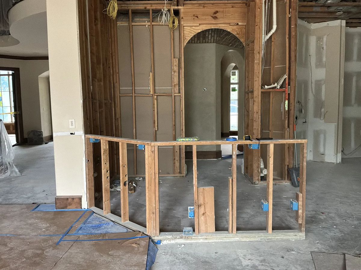 Partially constructed space with wooden framing, exposed drywall, and arched opening.