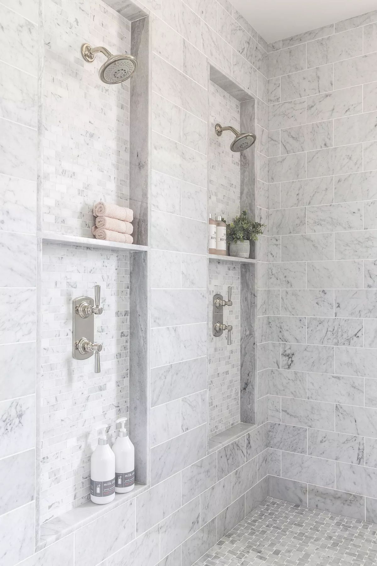 Bathroom with walk-in shower, marble tile walls, built-in niches, and pebble stone floor.