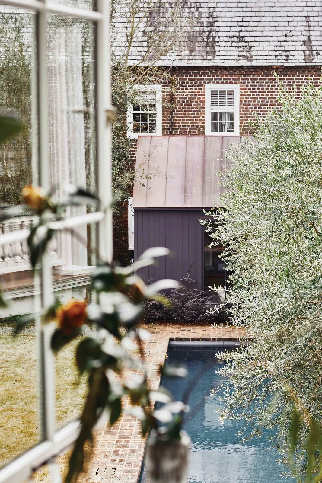 Garden area with blue pool, small shed, grass, plants, and brick pathways from the main house.