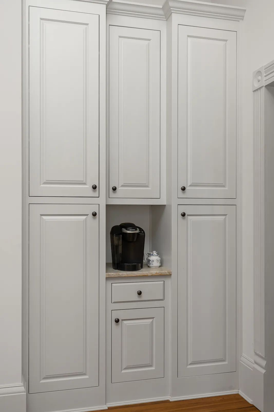 Space with white cabinets, coffee maker, and countertop between upper cabinets.