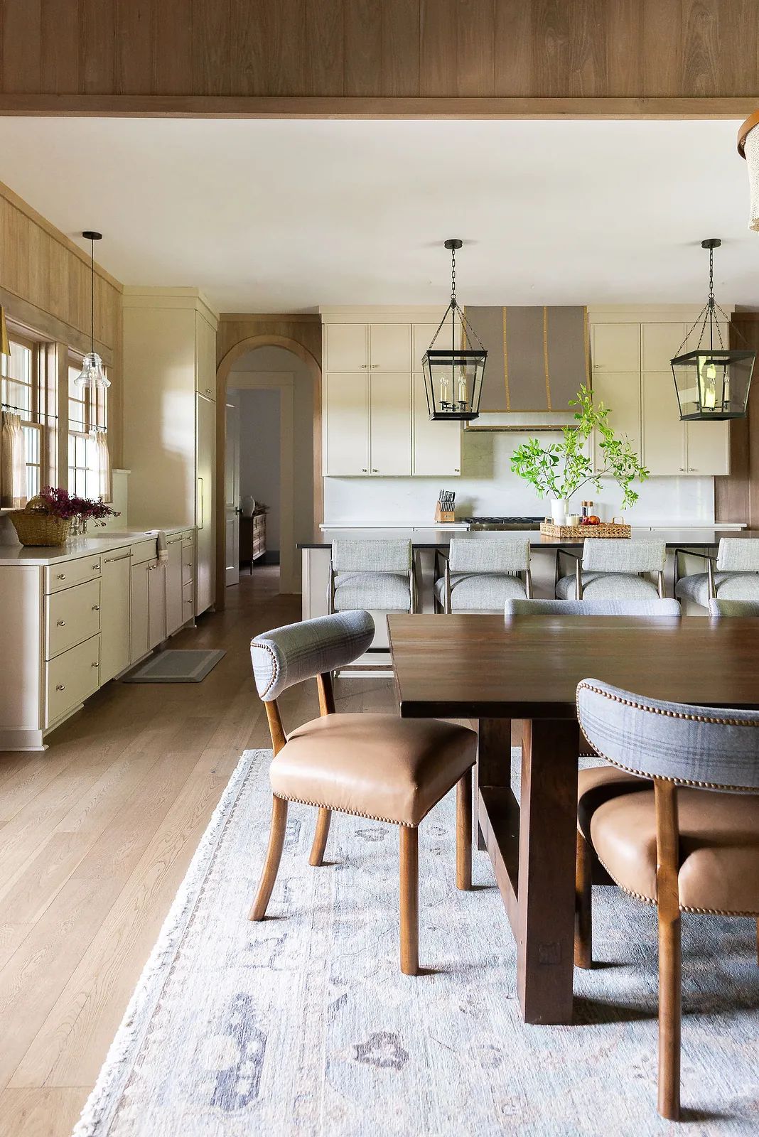 Dining room with wooden table, leather chairs, patterned rug, and pendant lights.
