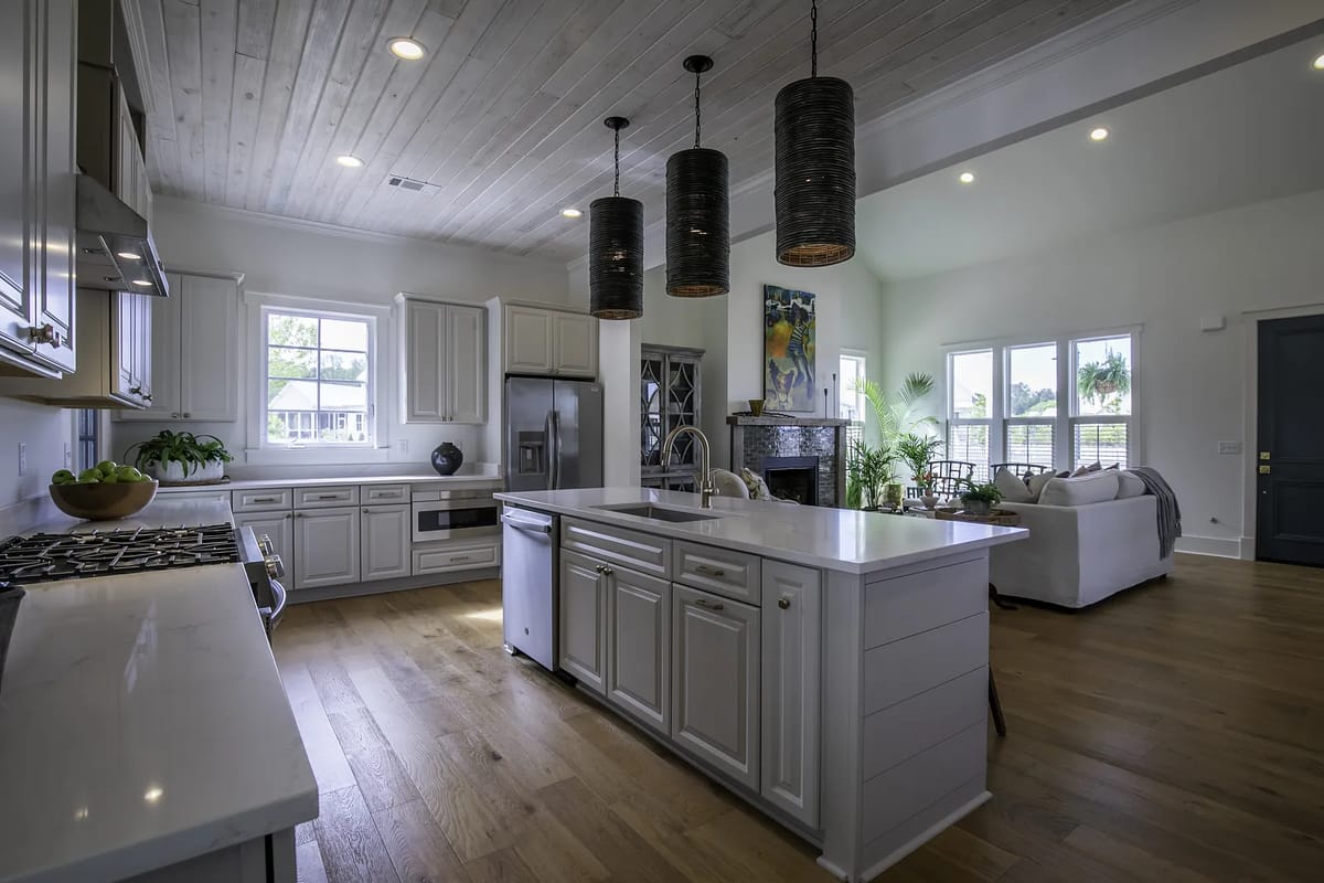 Kitchen with white cabinetry, central island, stainless steel appliances, and wooden floors.