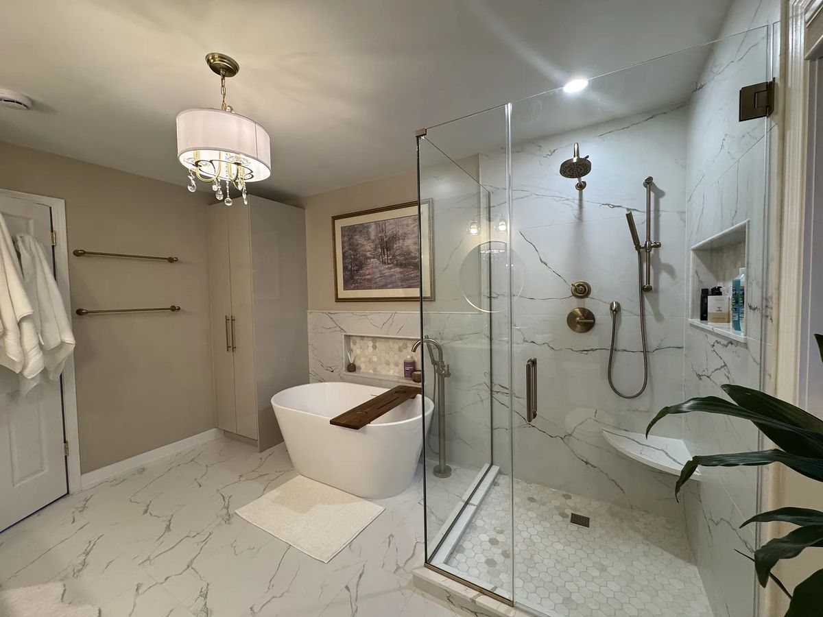 Bathroom with freestanding tub, glass shower, beige walls, large mirror, and marble floor.