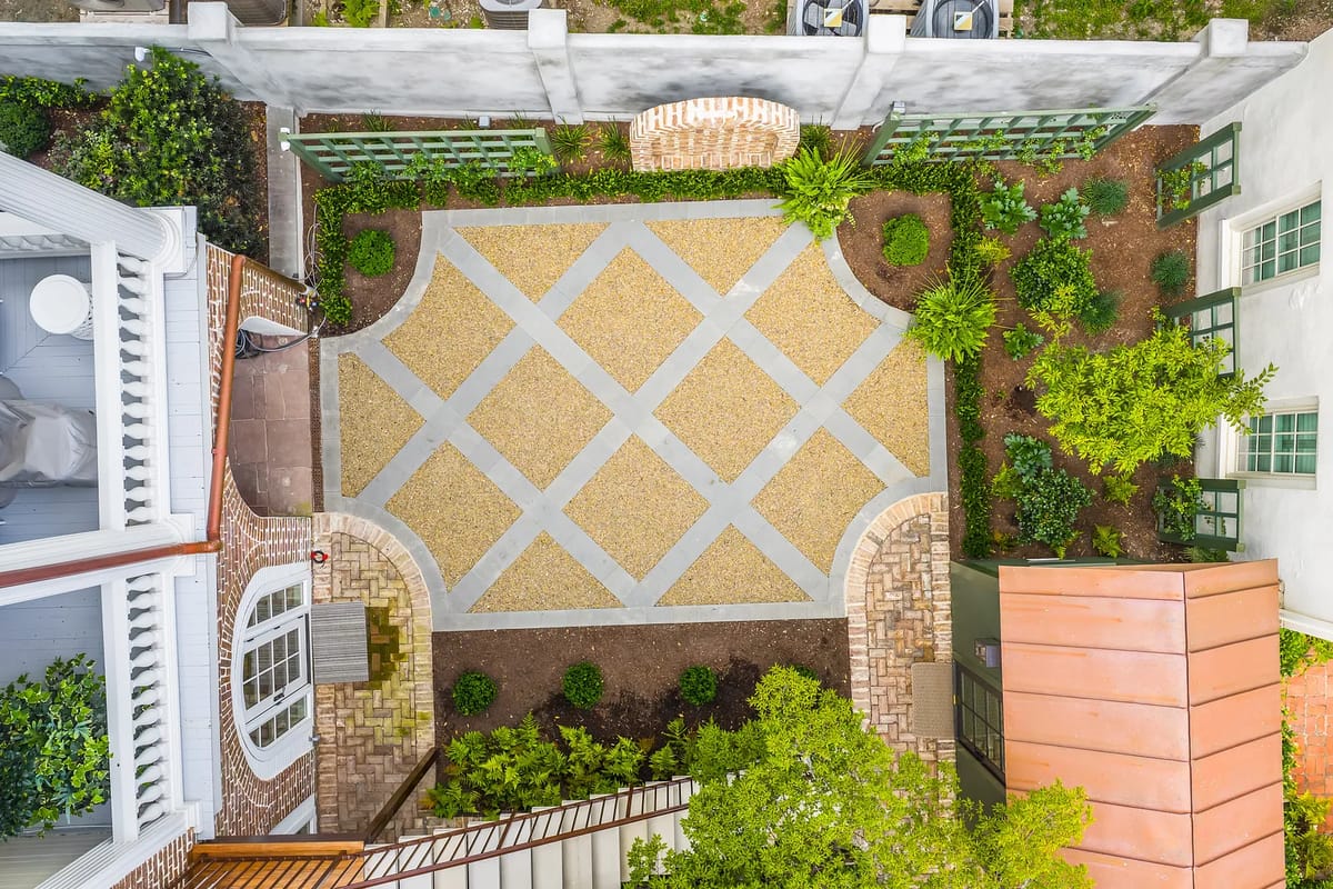 Garden with geometric gravel pathway, surrounded by shrubs, trees, and stone walls.