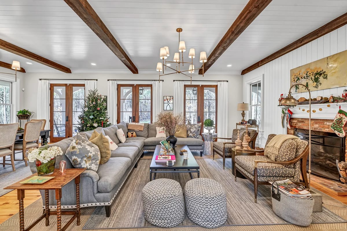 Living room with gray sectional sofa, coffee table, patterned armchairs, and fireplace decorated for the holidays.