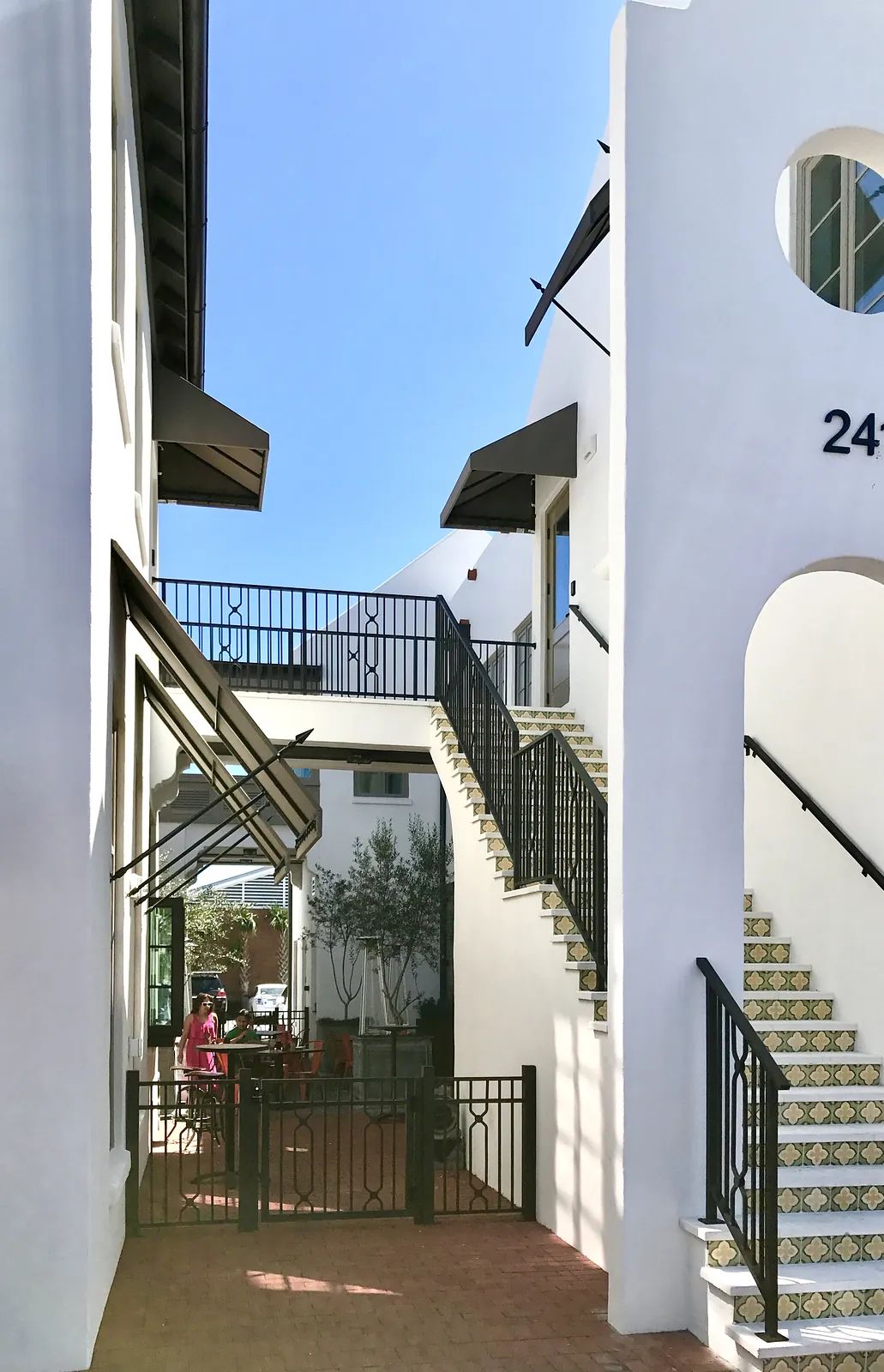 Front exterior view with white stucco, iron railings, tiled stairs, and outdoor seating.