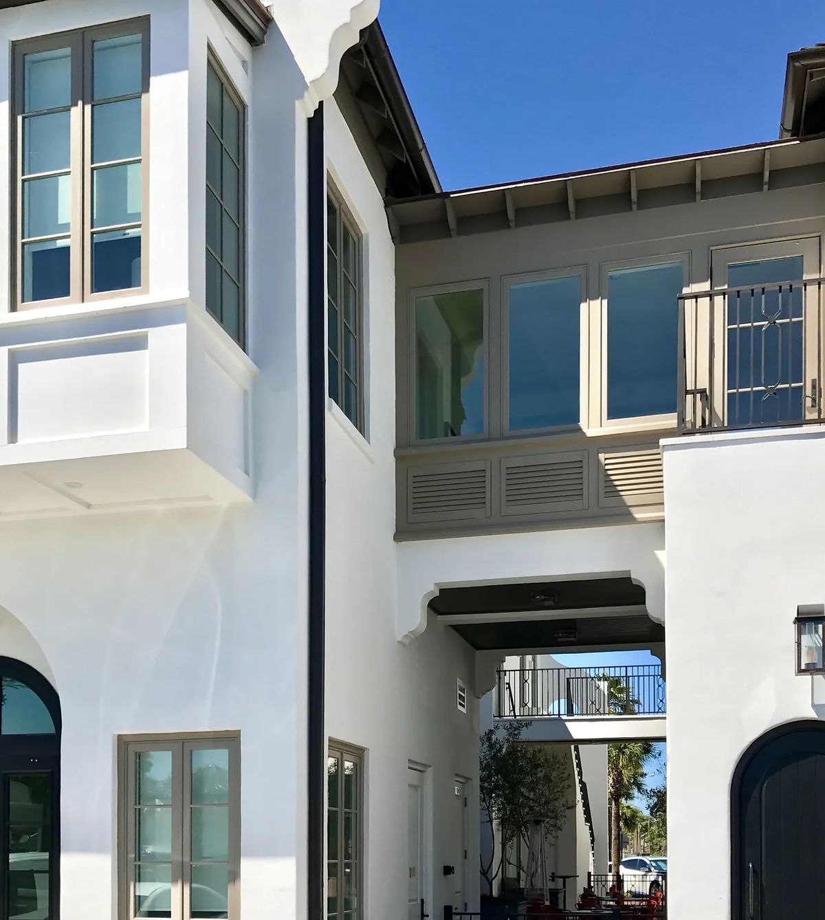 Exterior front view of a two-story building with white stucco, large windows, and a balcony.