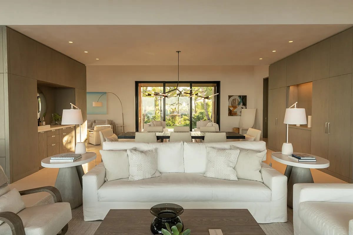 Living room with white sofa, coffee table, side tables, area rug, large windows, and built-in cabinetry.