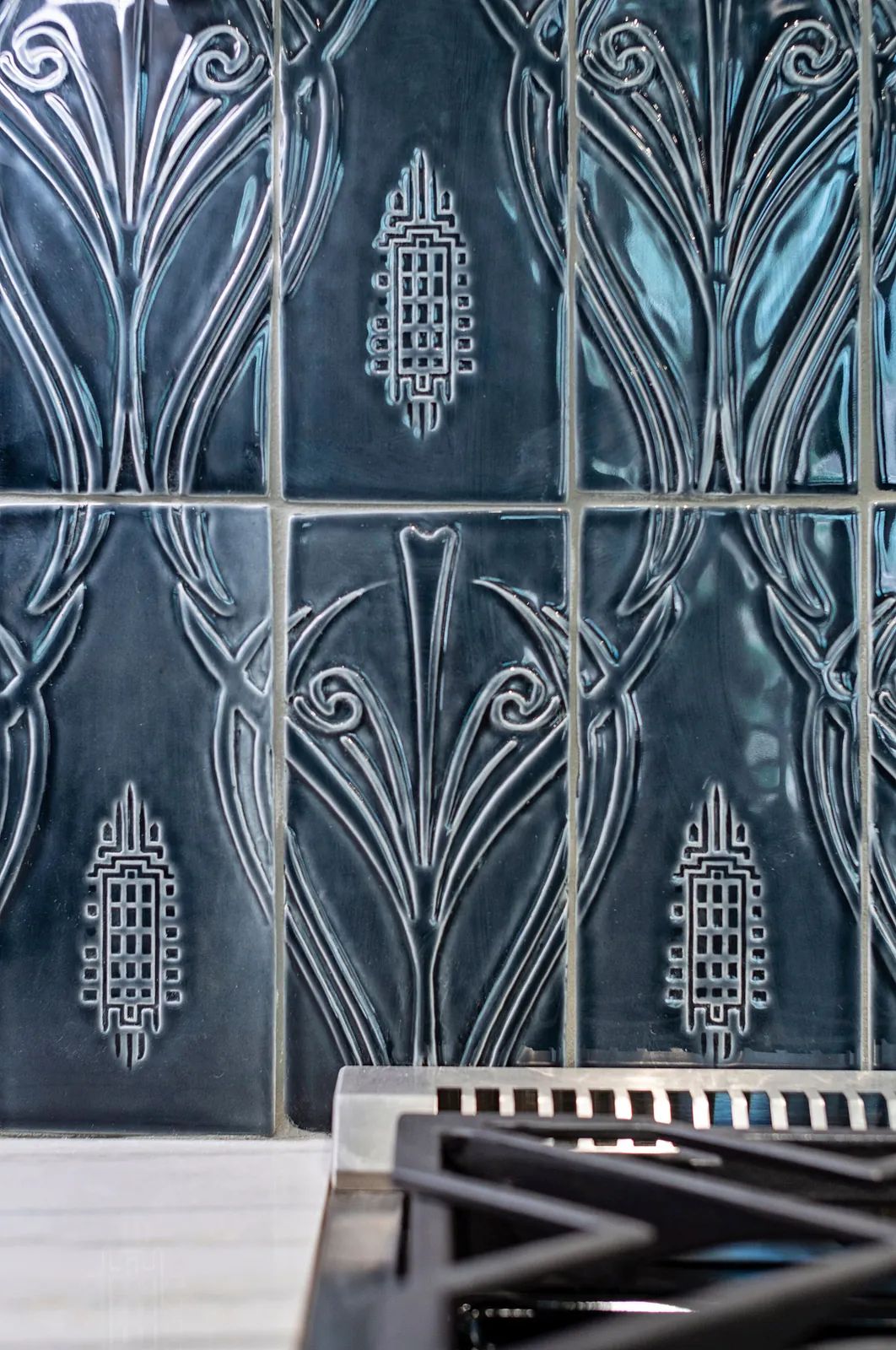 Kitchen with blue embossed tile backsplash and black stovetop.