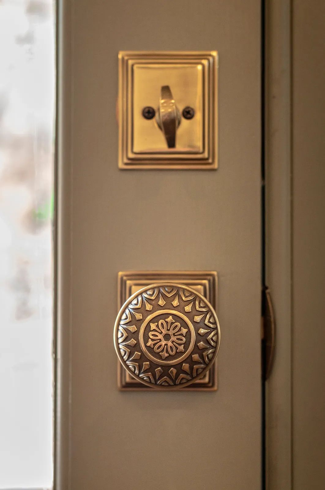 Close-up of ornate brass door knob and lock plate with floral pattern.