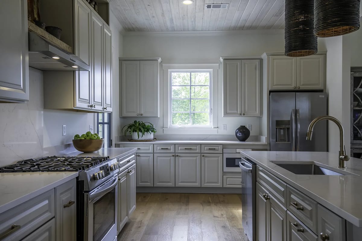 Kitchen with gray cabinetry, marble countertop, stainless steel appliances, and a large window with greenery.