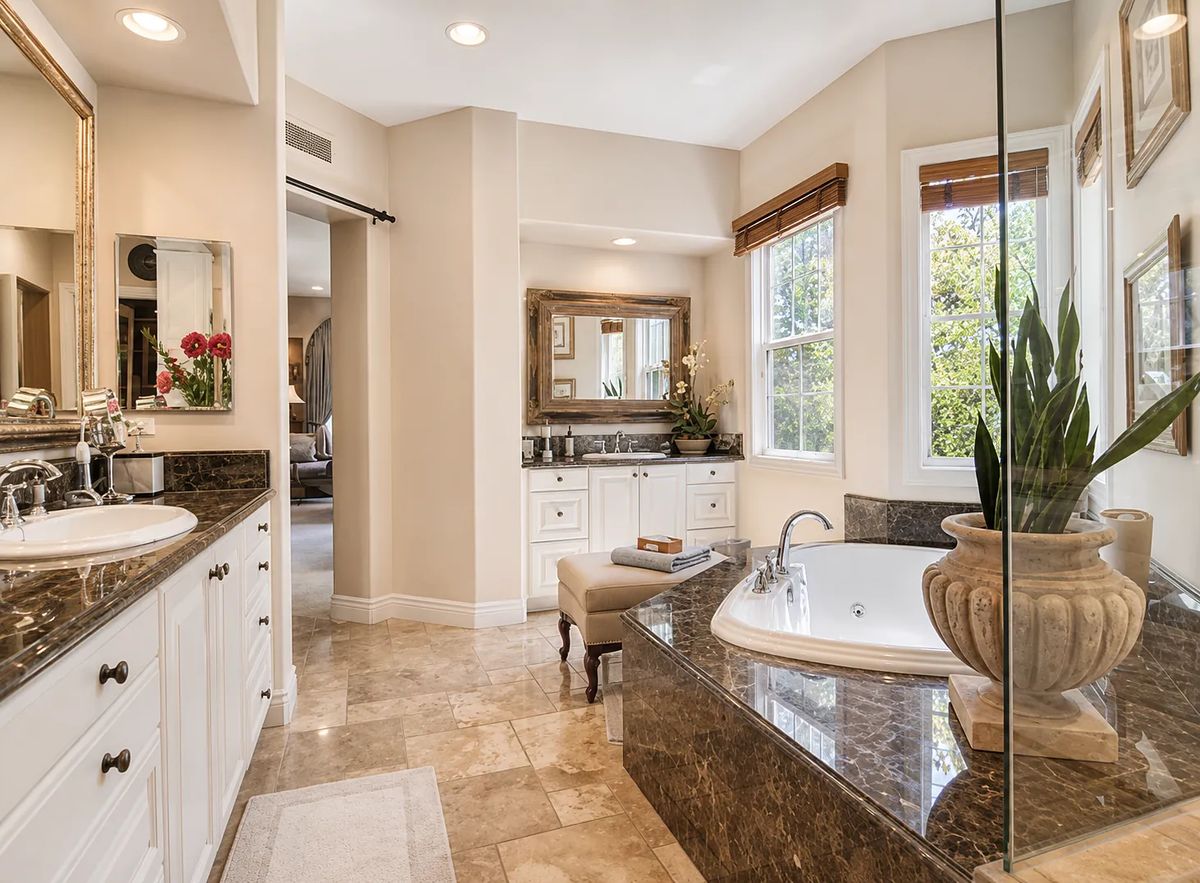 Bathroom with double sinks, soaking tub, glass shower, and natural light from window.