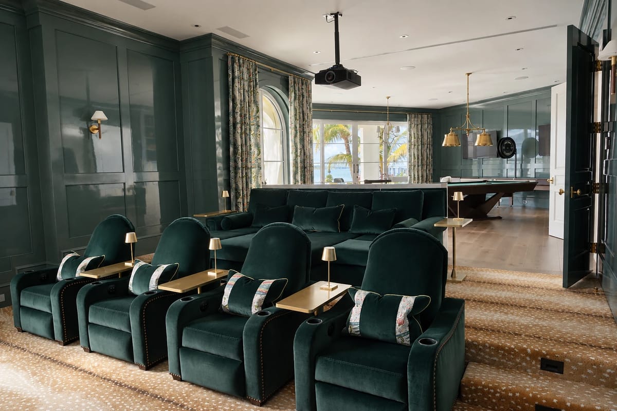 Living room with dark green walls, sectional sofa, reclining chairs, and projector.