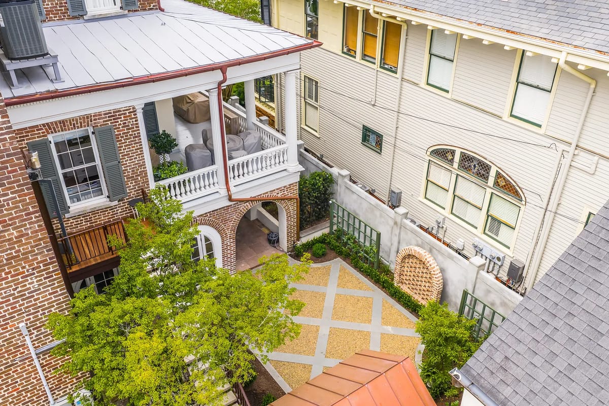 Exterior view of a brick building with balcony, courtyard, and adjacent multi-pane window building.