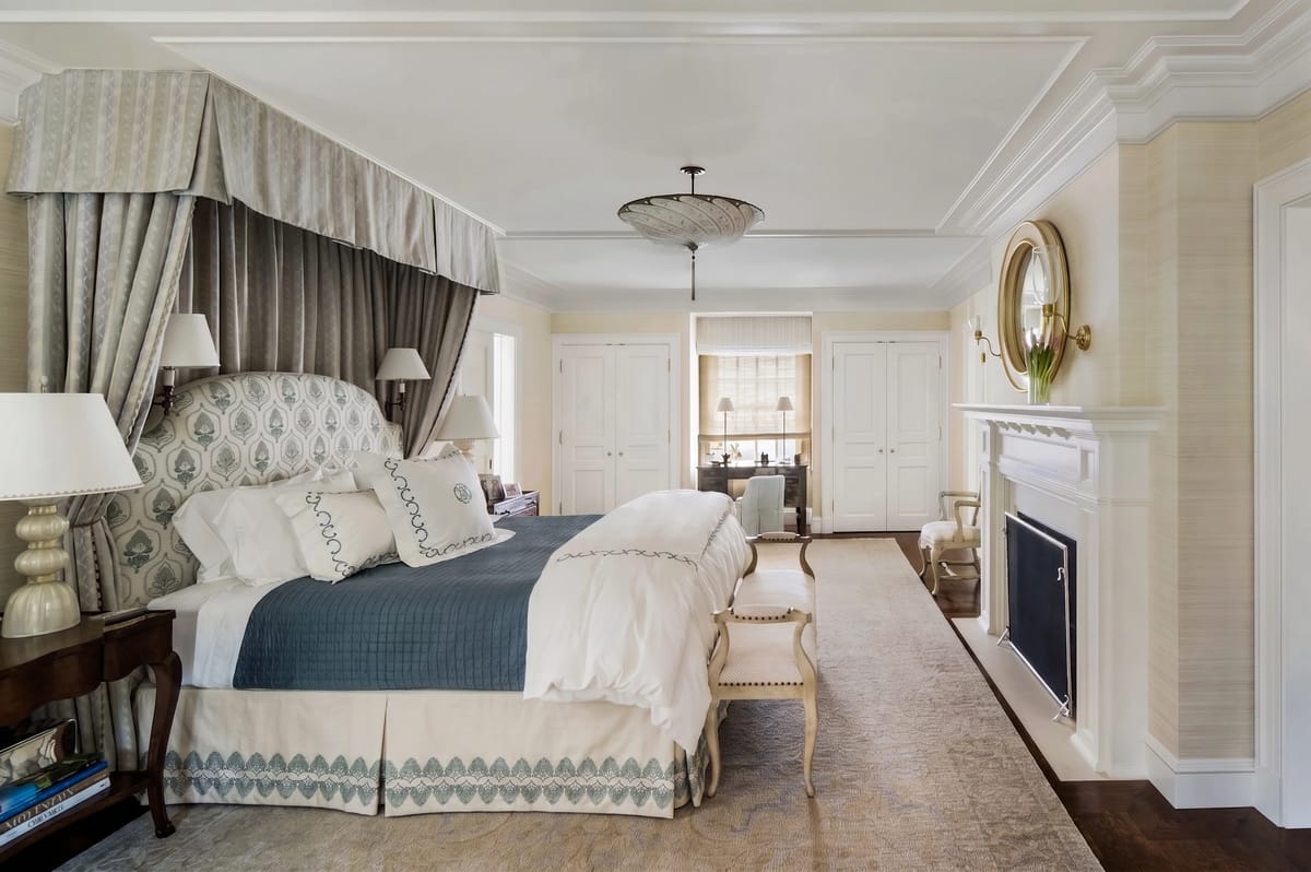 Bedroom with canopy bed, quilt, nightstands, lamps, chandelier, and fireplace.