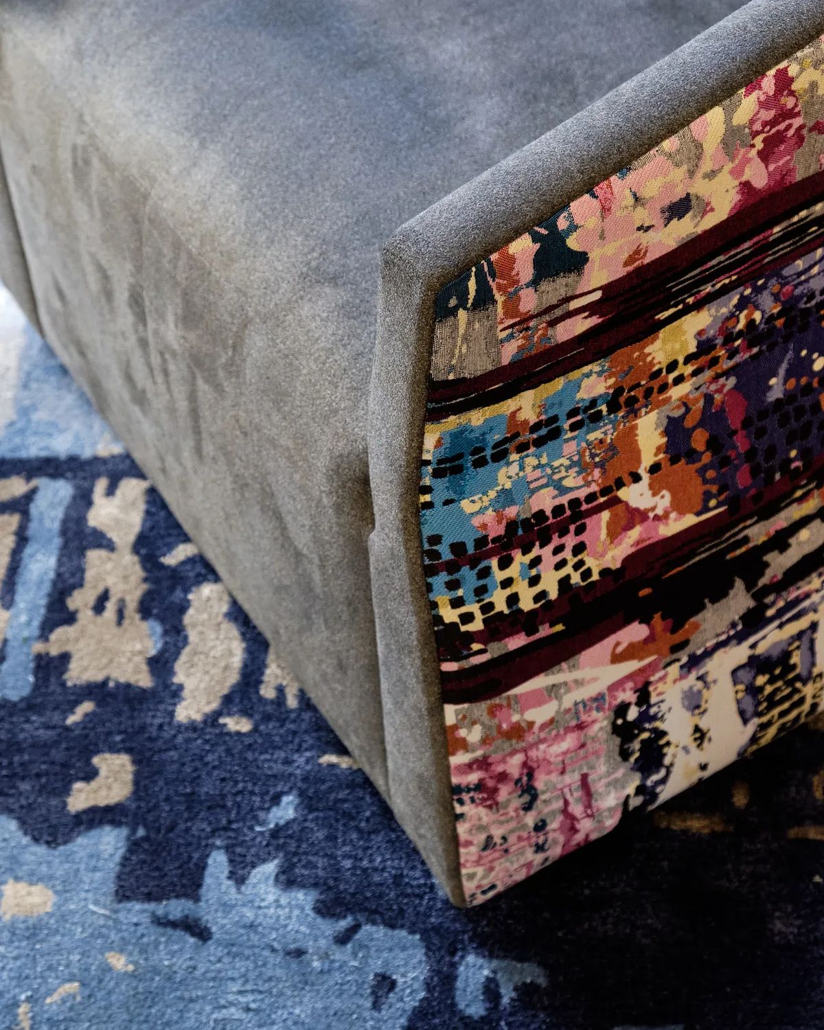 Close-up of textured gray surface with colorful edge patterns and a blue area rug.