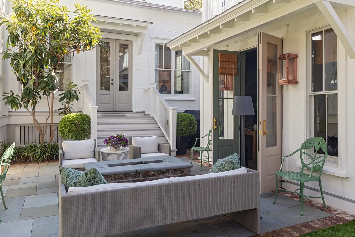 Outdoor patio with sectional sofa, coffee table, green chairs, and potted plants.