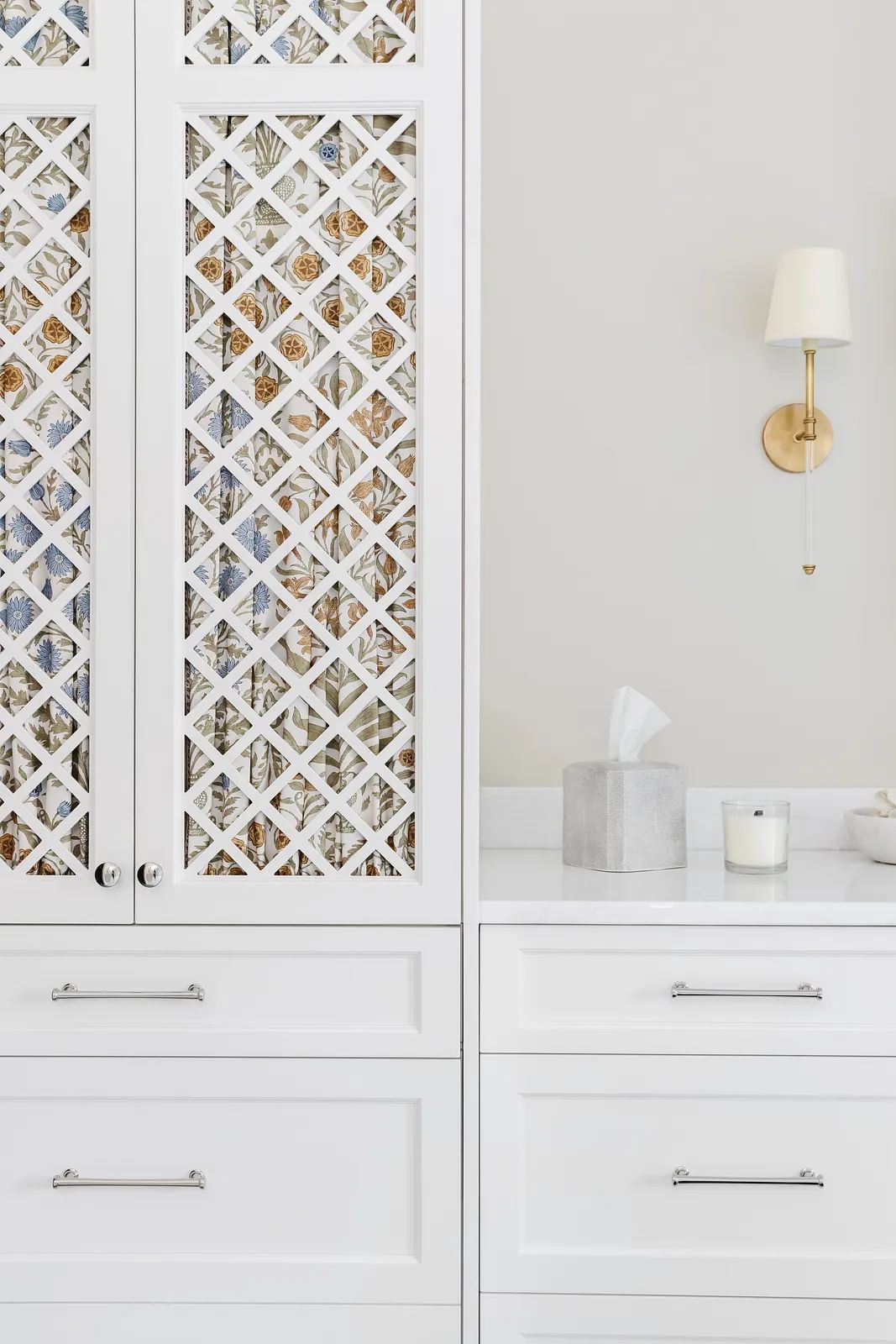 Kitchen with white cabinetry, marble countertop, sconce, and decorative glass pattern.