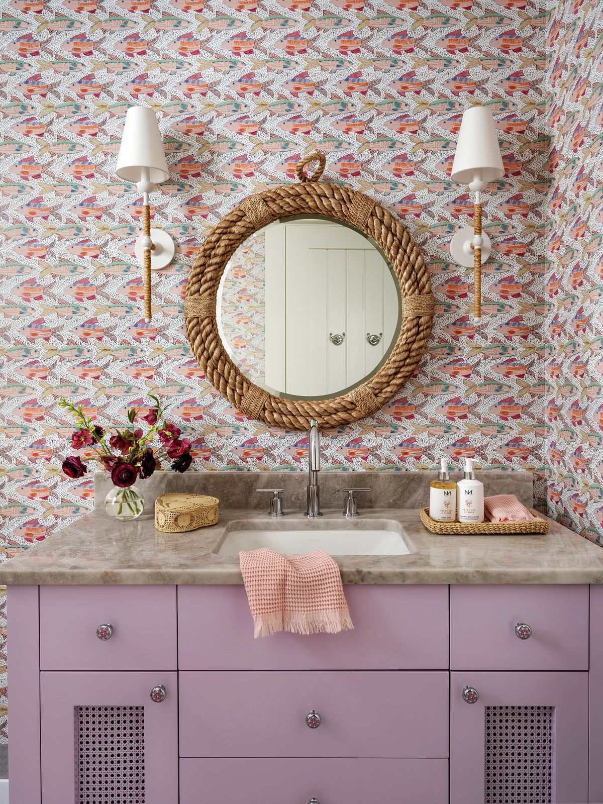 Bathroom with purple vanity, marble countertop, rope-framed mirror, and decorative items.