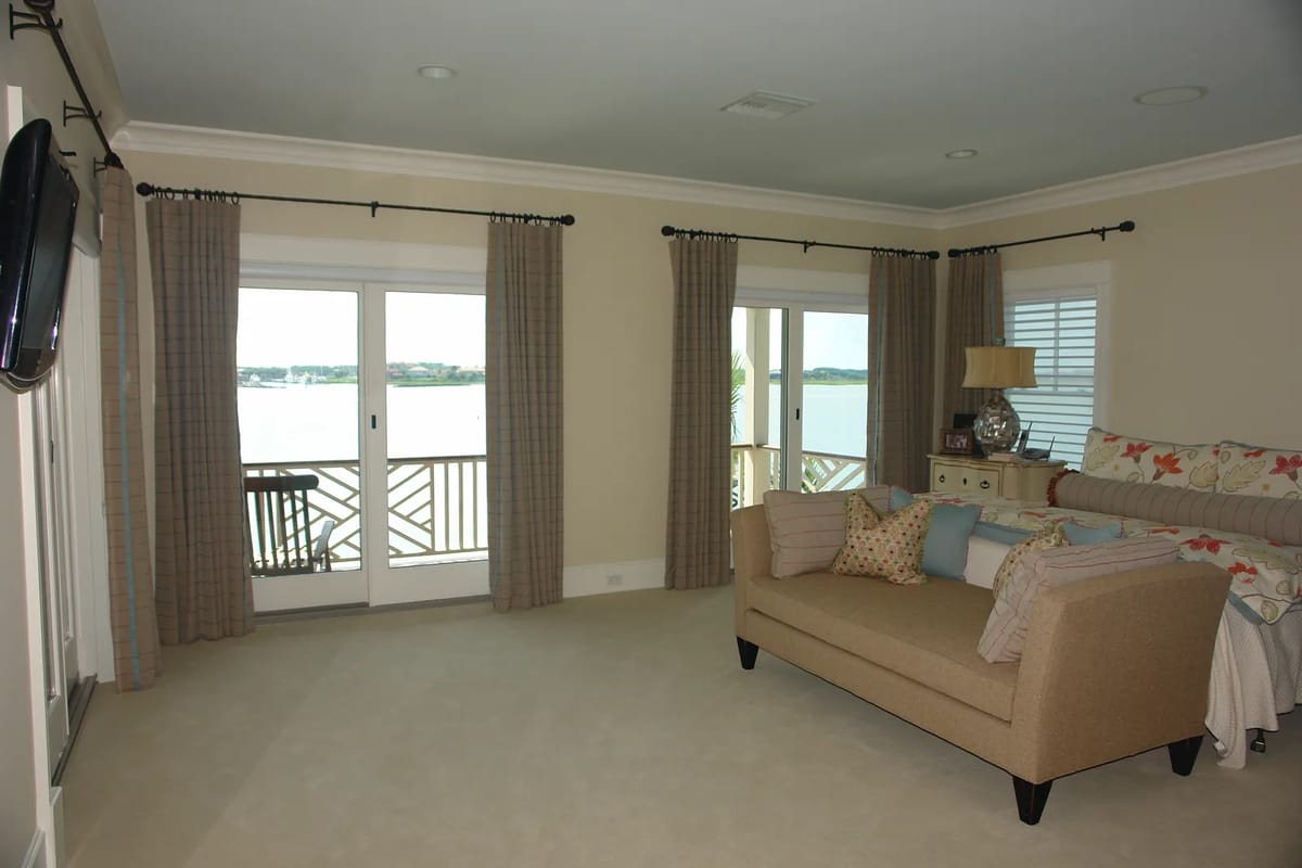 Living room with beige sofa, area rug, curtains, sliding doors, and waterfront view.