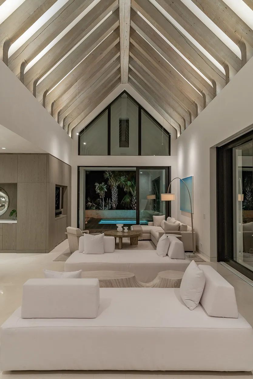 Living room with sectional sofa, coffee table, sliding glass doors, and vaulted ceiling with exposed beams