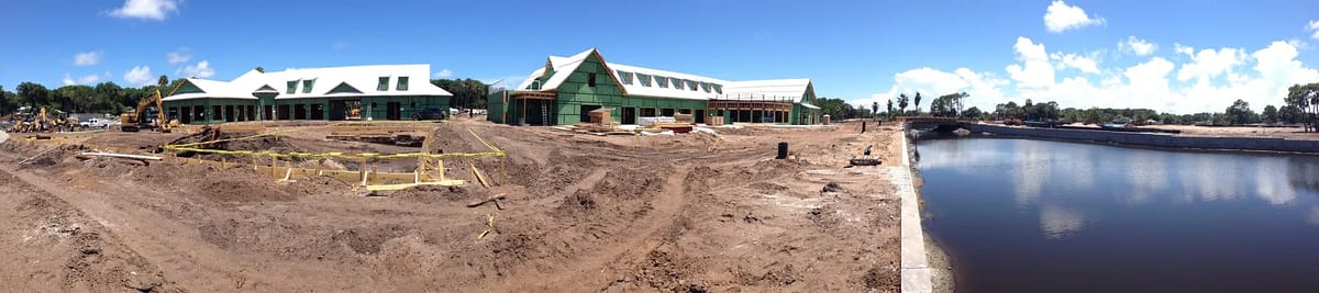 Outdoor construction site with buildings, materials, vehicles, and a river.
