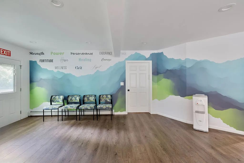 Room with abstract mural, four chairs, water cooler, and wood flooring