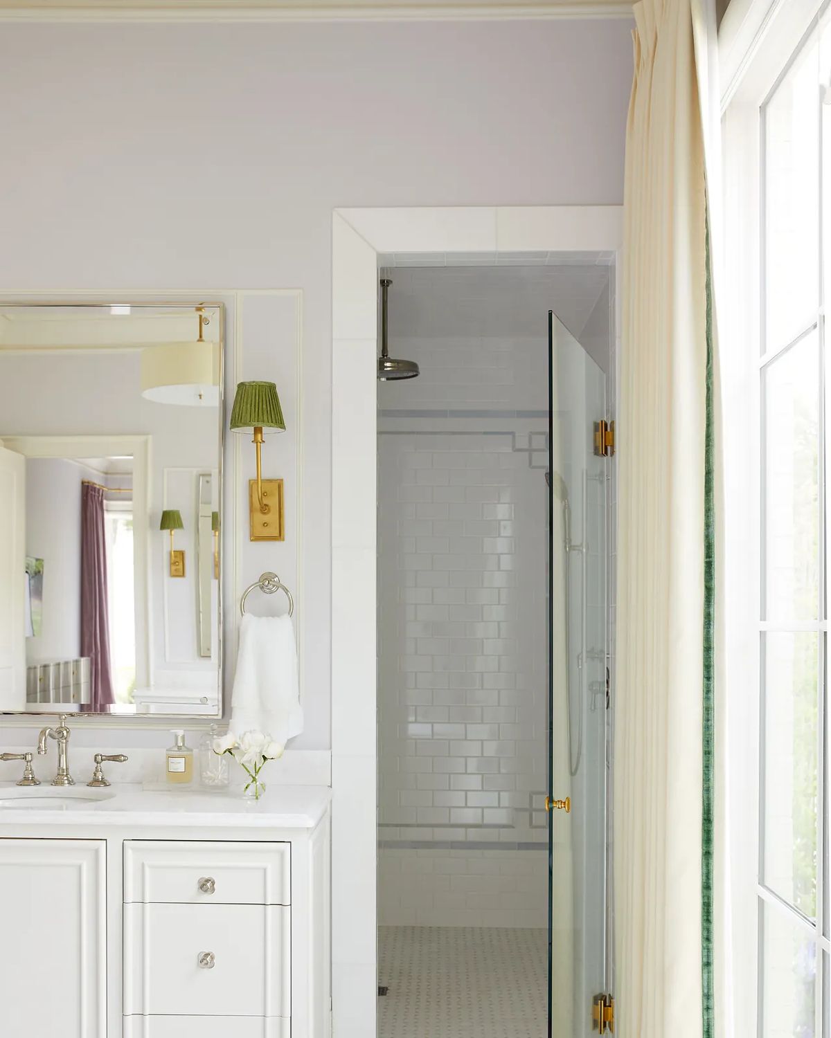 Bathroom with white cabinetry, marble countertop, large mirror, glass shower, and natural light from window