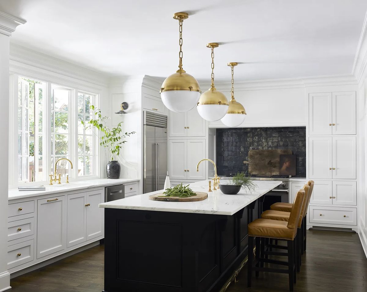 Kitchen with white cabinets, marble island, brass pendant lights, and dark wood flooring
