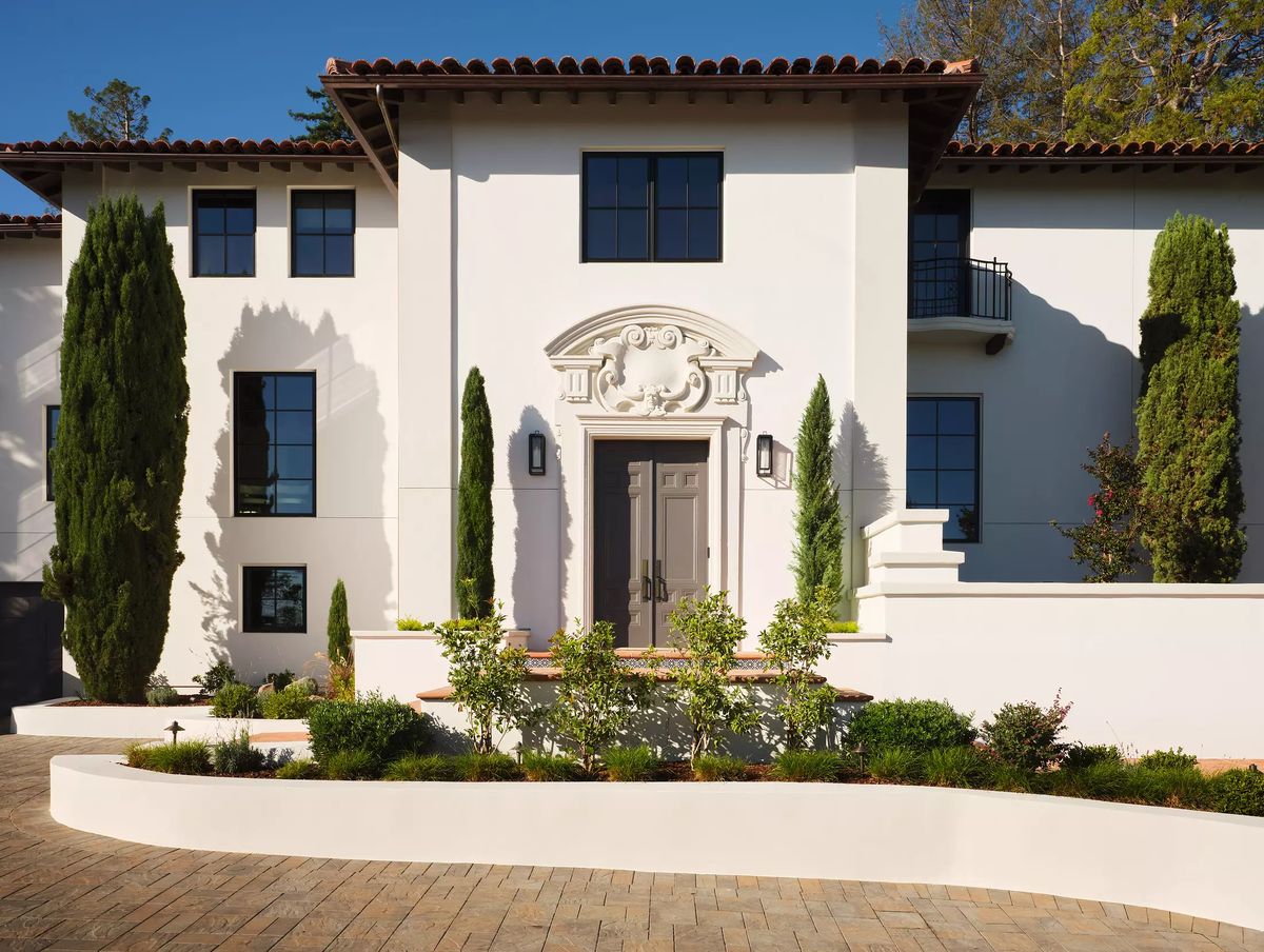 Front exterior of a house with decorative entrance, tall windows, and symmetrical landscaping.