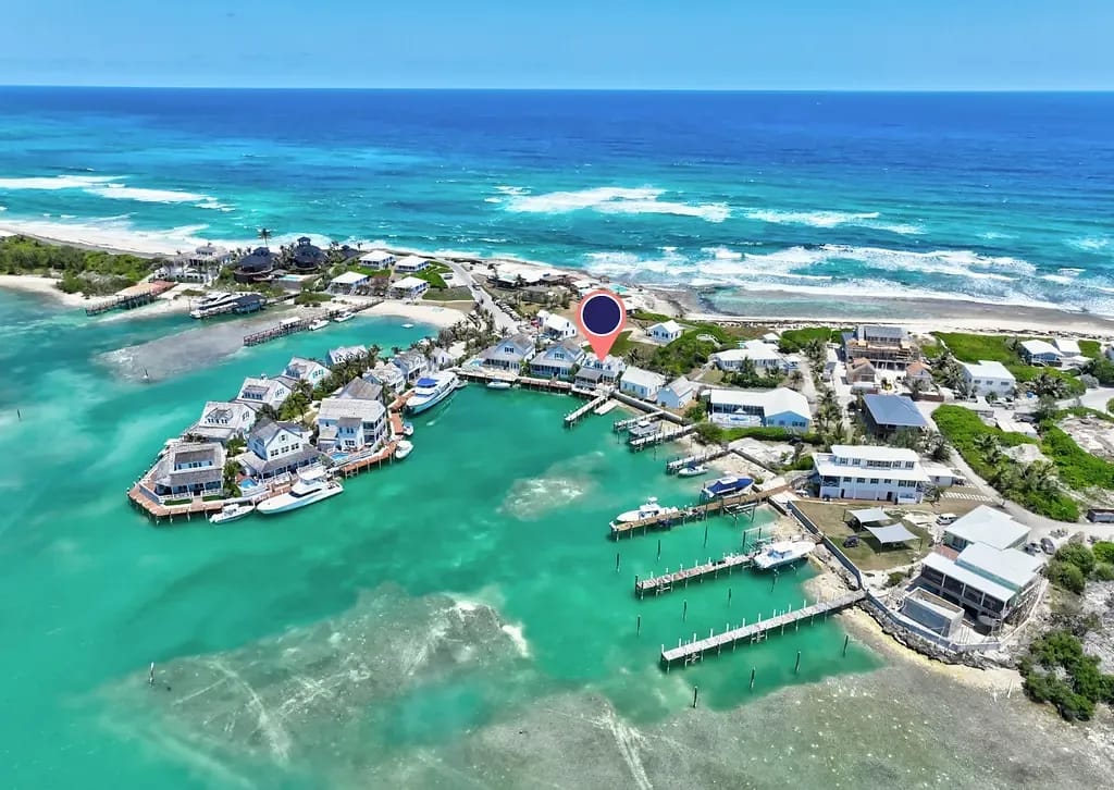 Aerial view of coastal community with houses, docks, and turquoise water.