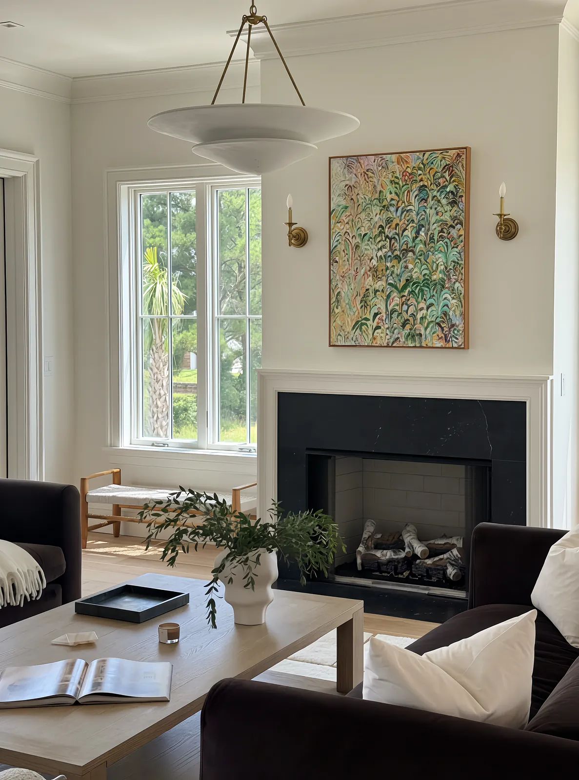 Living room with dark sofa, light wood coffee table, area rug, large windows, black fireplace, and abstract artwork.
