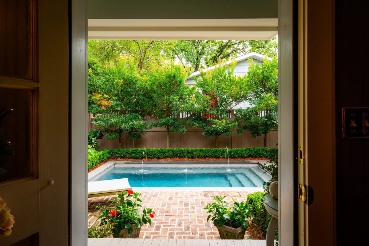 Exterior rear view with swimming pool, landscaped garden, and brick patio.