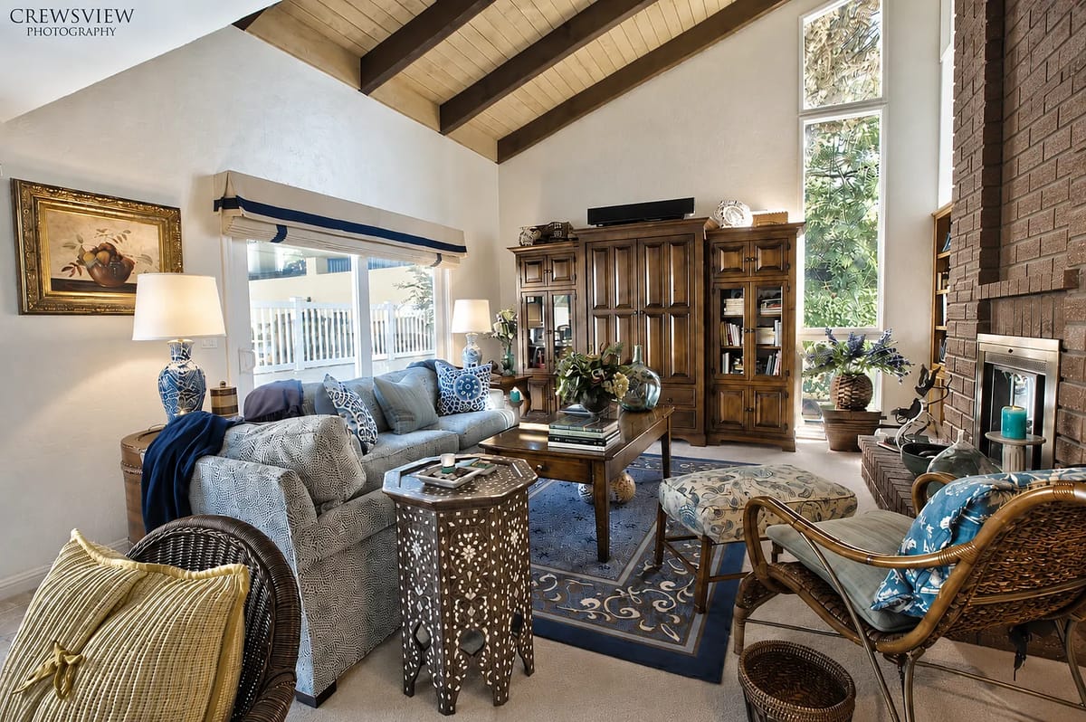 Living room with gray sofa, wooden coffee table, and large windows letting in natural light.