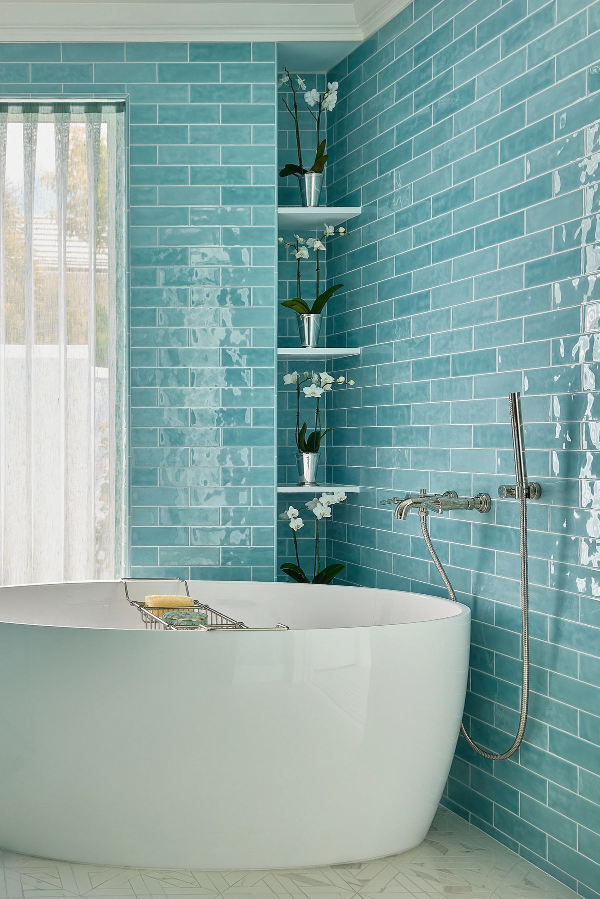 Bathroom with freestanding bathtub, turquoise tile walls, and built-in shelves with potted plants