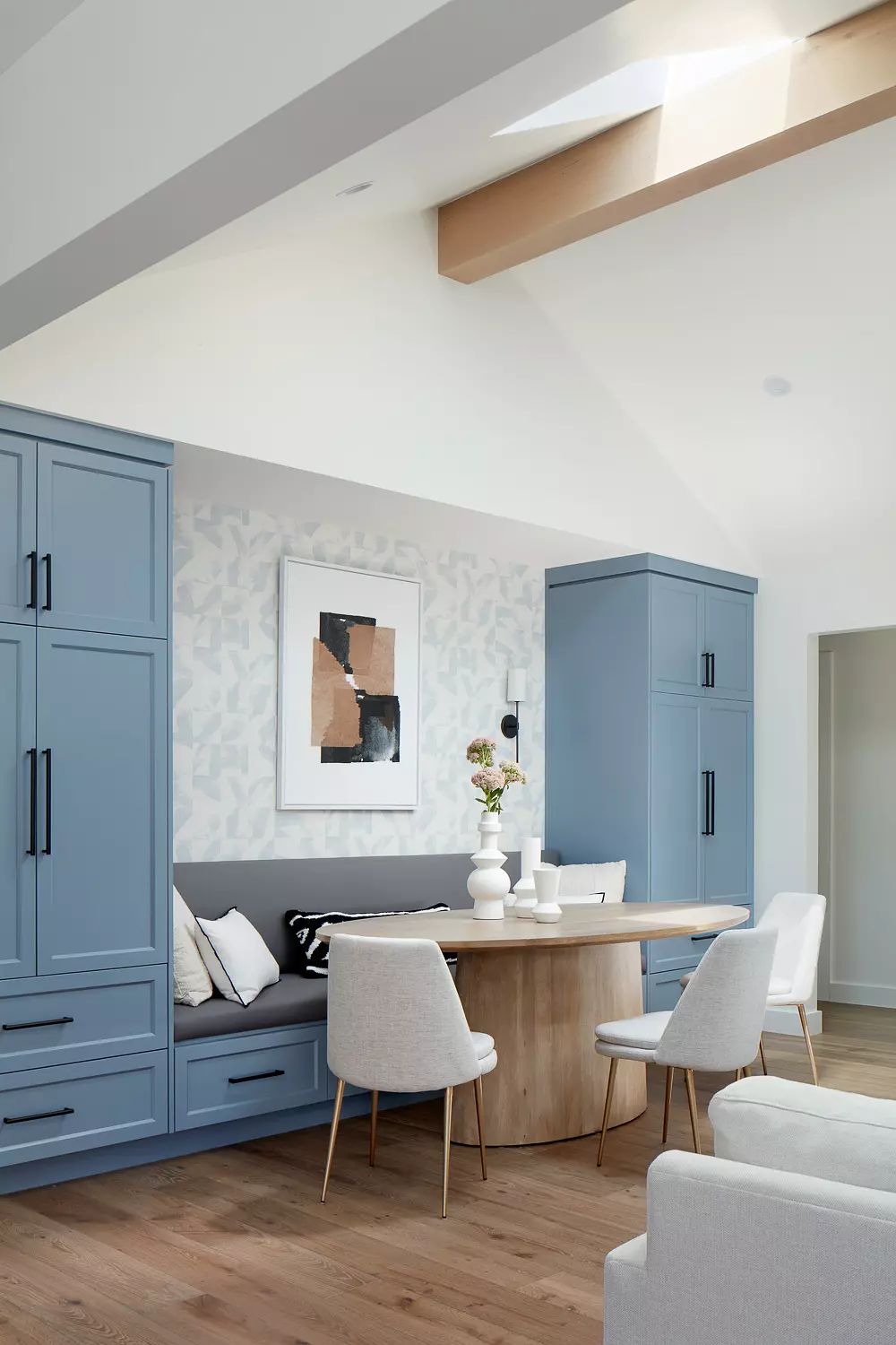 Multi-functional space with blue cabinetry, round table, white chairs, and geometric patterned walls.