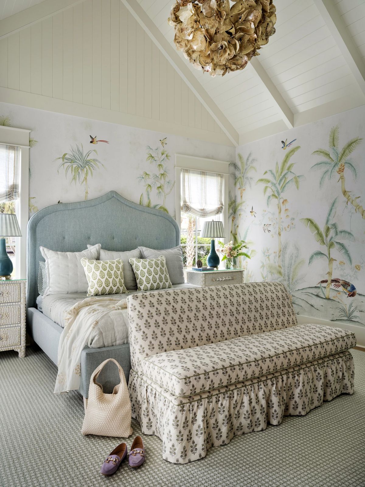 Bedroom with blue bed, settee, floral wallpaper, and bedside lamps