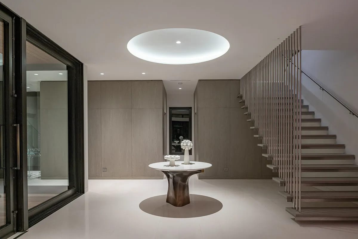 Foyer with round table, wood walls, staircase, and circular ceiling light.