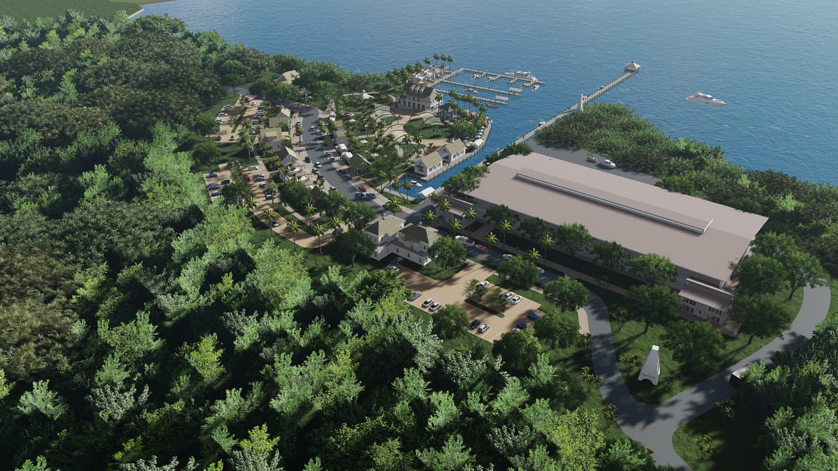 Aerial view of coastal area with marina, buildings, trees, and pathways.