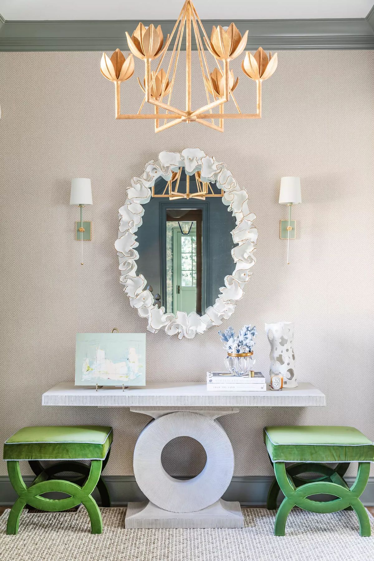 Foyer with a mirror, white console table, green stools, wall sconces, and wood chandelier.