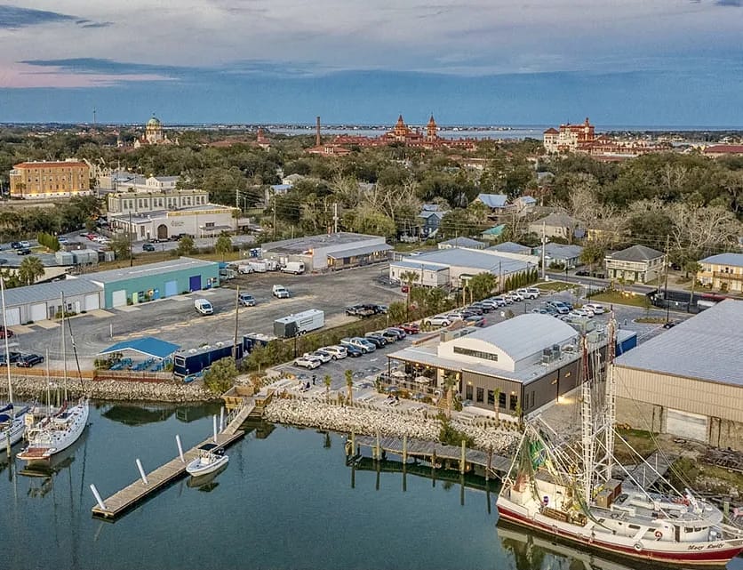 Aerial view of a marina with boats, commercial buildings, warehouses, and a waterway.