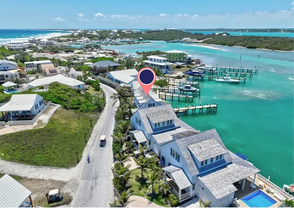Aerial view of a coastal community with residential buildings, harbor, and turquoise water.