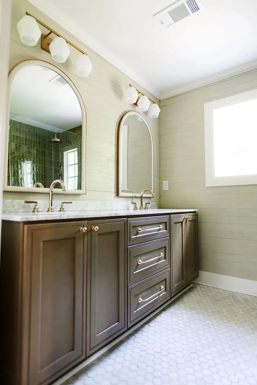 Bathroom with double vanities, marble countertop, round mirrors, and hexagonal tiled floor.