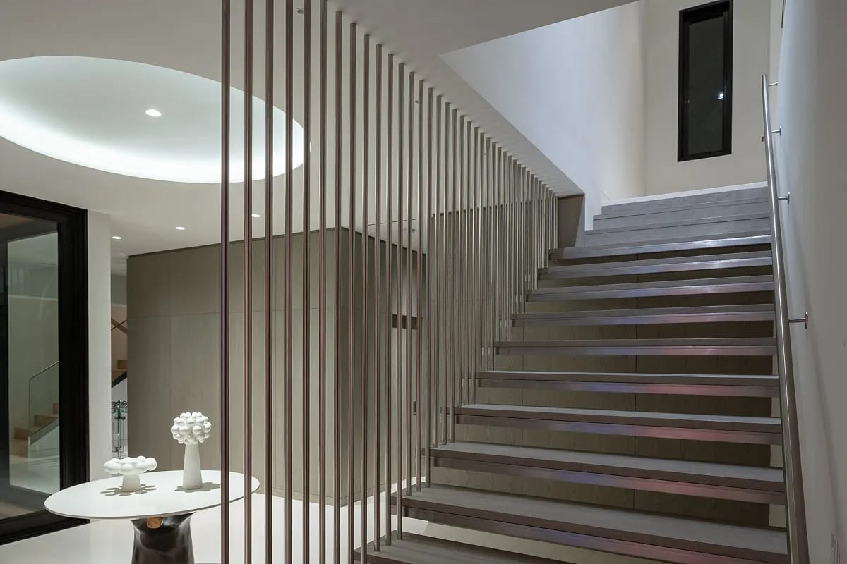 Foyer with wooden staircase, round table, decorative object, and high ceiling with recessed light